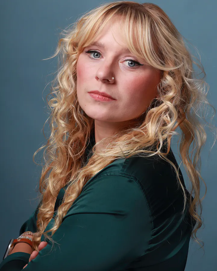 Detective casting direction with a deep teal top, cool blue background, and focused expression