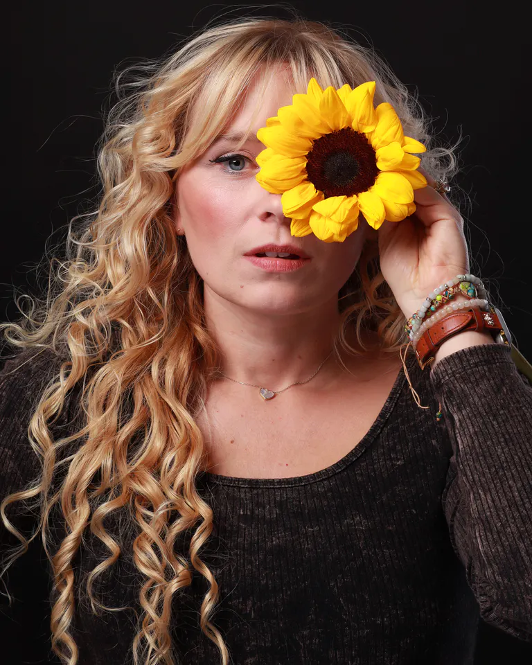 Woman holding a sunflower during a self-portrait session at HQ Portraits in Charlotte